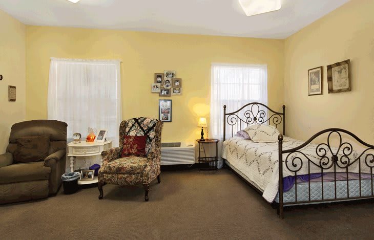 A cozy bedroom with a decorative chair, metal bed frame, and warm lighting.