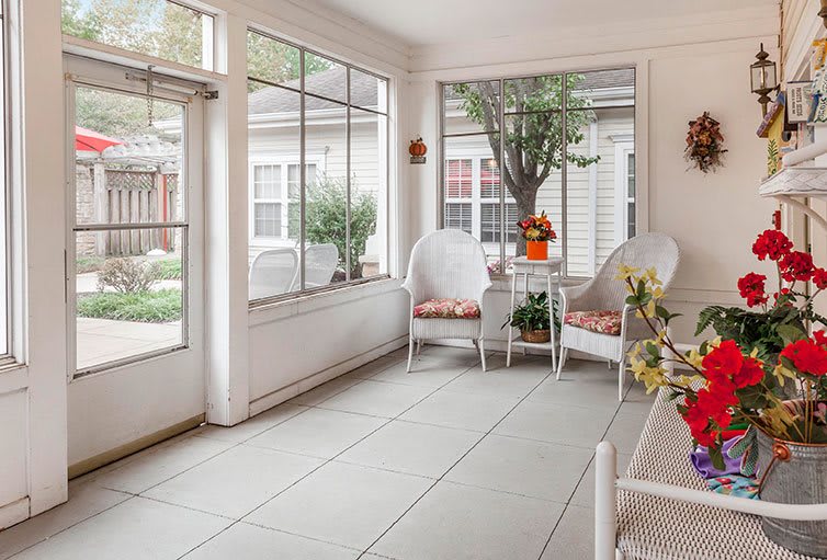 A bright and cozy sunroom with comfortable seating and a garden view.
