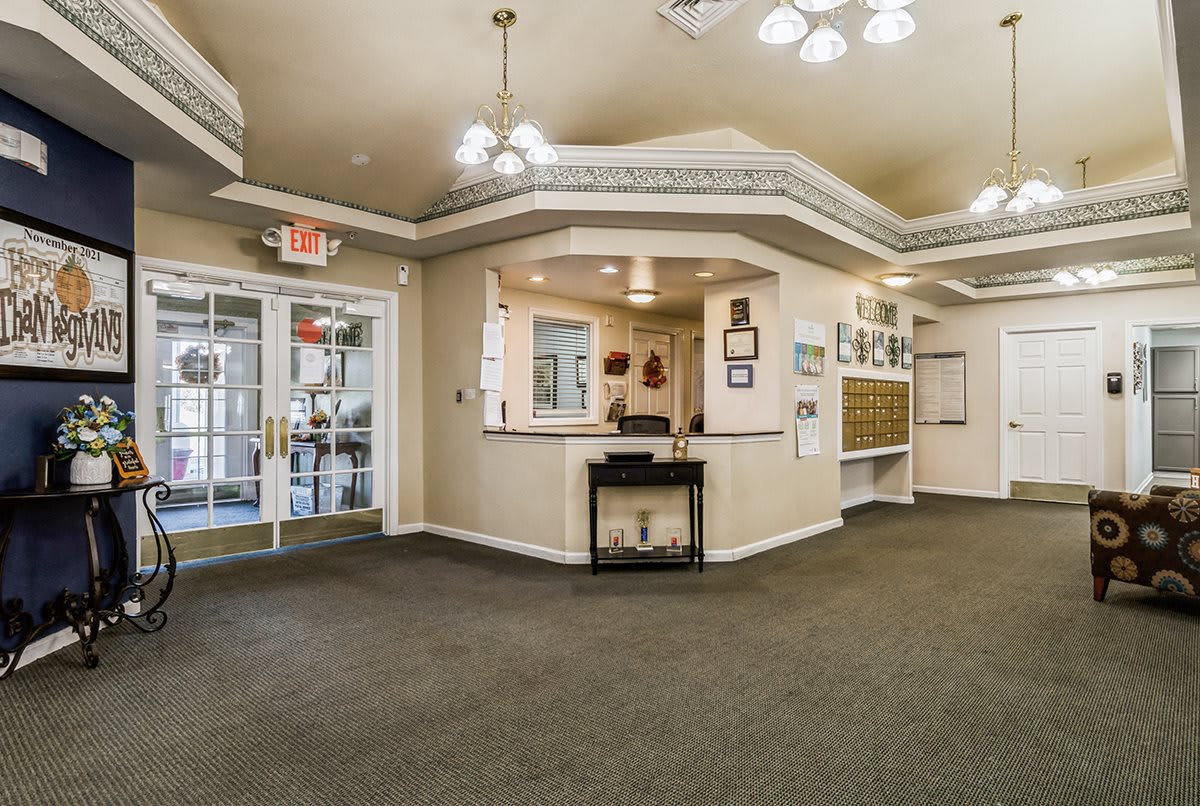 A spacious lobby with a reception desk, overhead lighting, and entrance doors.