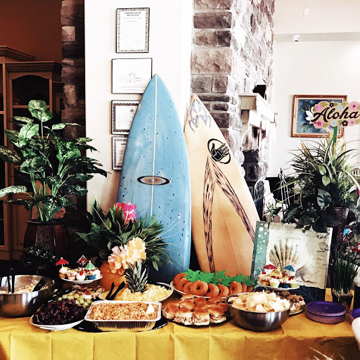 A vibrant tropical-themed buffet featuring a variety of dishes, accented by surfboards and lush greenery.