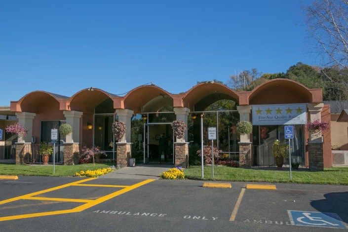 A building with arch-shaped entrances and a parking lot under a clear blue sky.