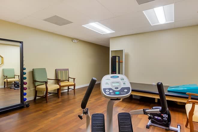 A small fitness room with an exercise bike and seating area on a wooden floor.