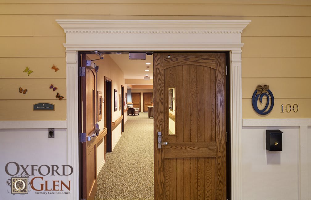 A corridor entrance featuring a wooden door leading to an interior hallway.