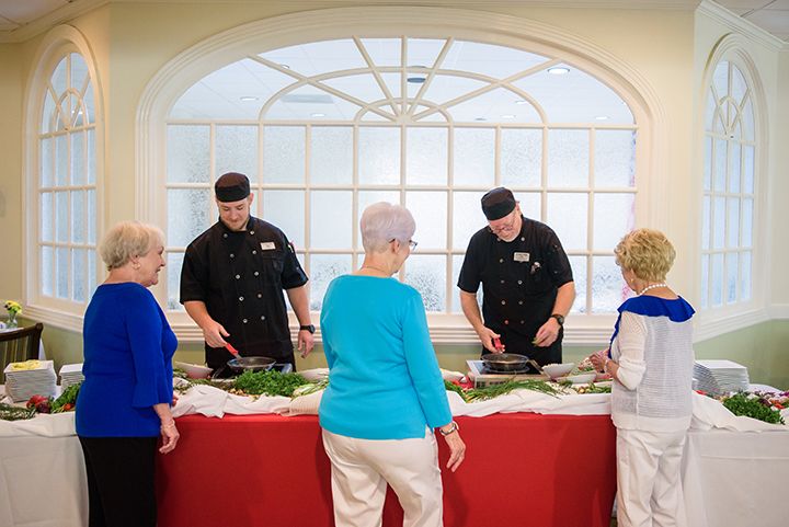 Chefs serving food to seniors at a buffet event.