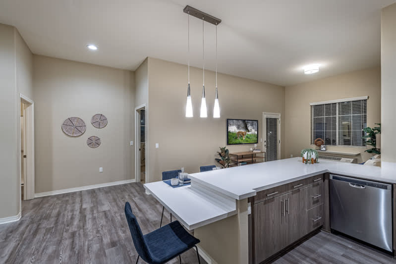A modern kitchen with an island and pendant lighting, featuring wood flooring and an open dining area.