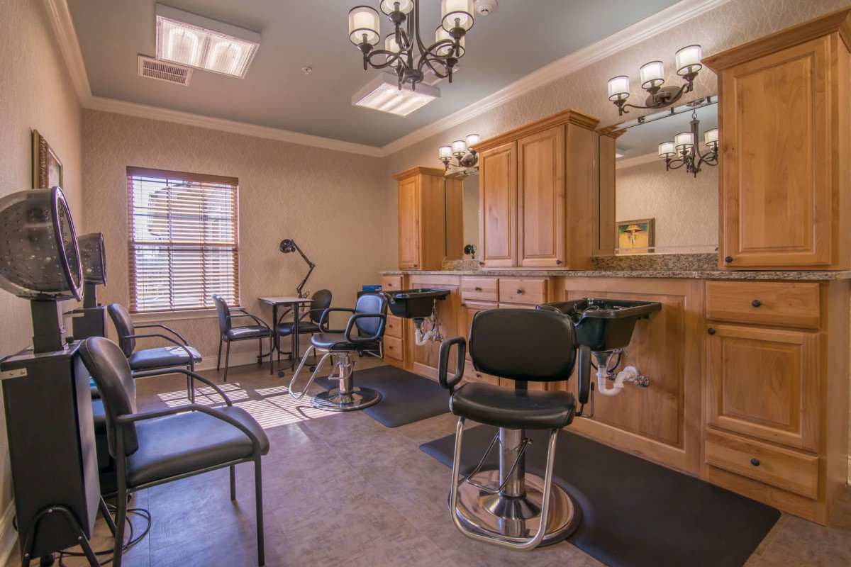 A well-lit hair salon with chairs and mirrors, featuring wooden cabinets and stylish lighting.
