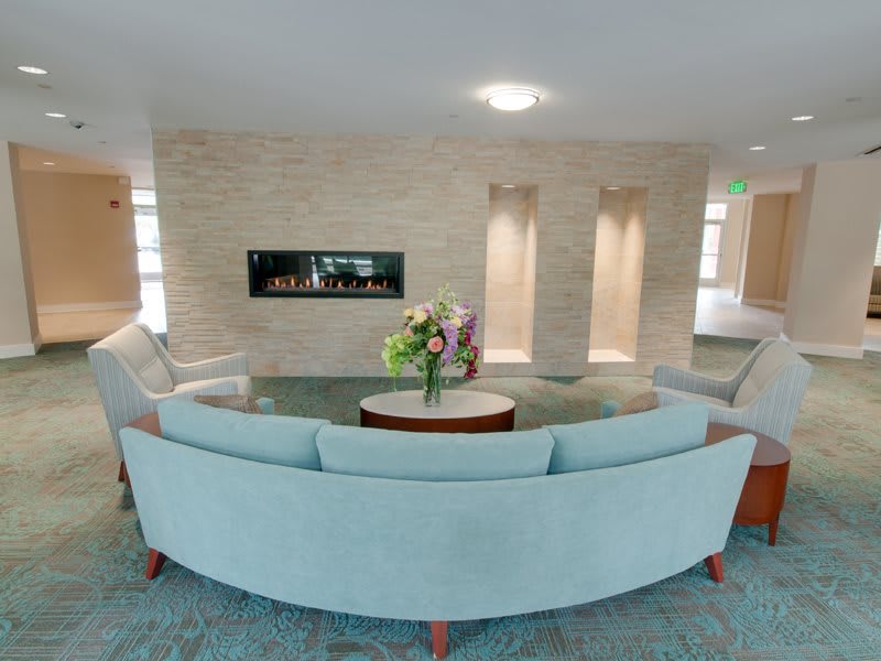 A modern living room with a circular sofa, centered coffee table, and a sleek fireplace.