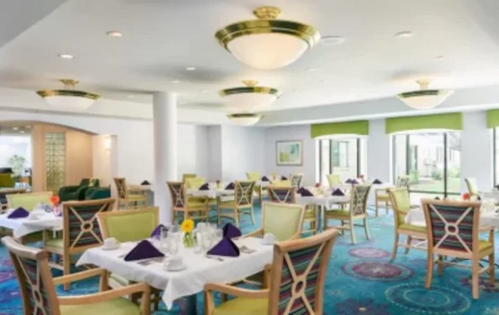 A well-decorated dining room with neatly arranged tables and elegant lighting fixtures.