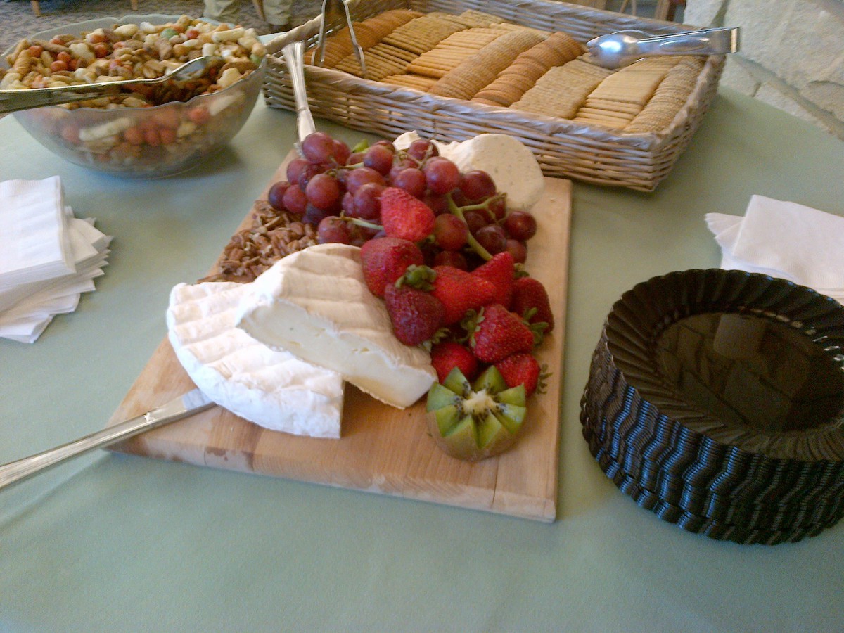 A cheese and fruit platter with grapes, strawberries, and crackers.