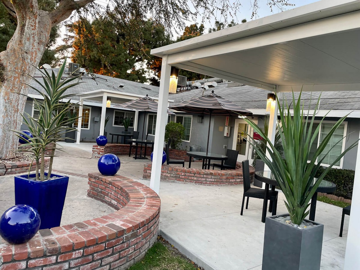 A modern outdoor patio area featuring contemporary furniture, brickwork, and decorative plants.