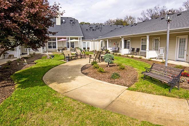 A well-maintained courtyard with a winding pathway, surrounded by benches and garden landscaping.