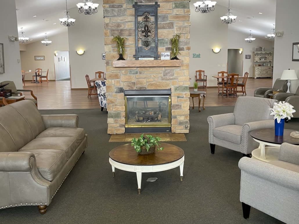A cozy living room with sofas and armchairs arranged around a fireplace and coffee table.