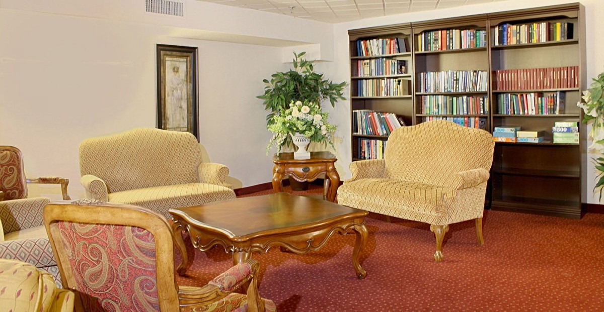 A cozy living room with elegant furniture, a wooden coffee table, and a bookshelf filled with books.