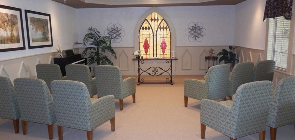 A small chapel interior with stained glass windows and arranged seating.