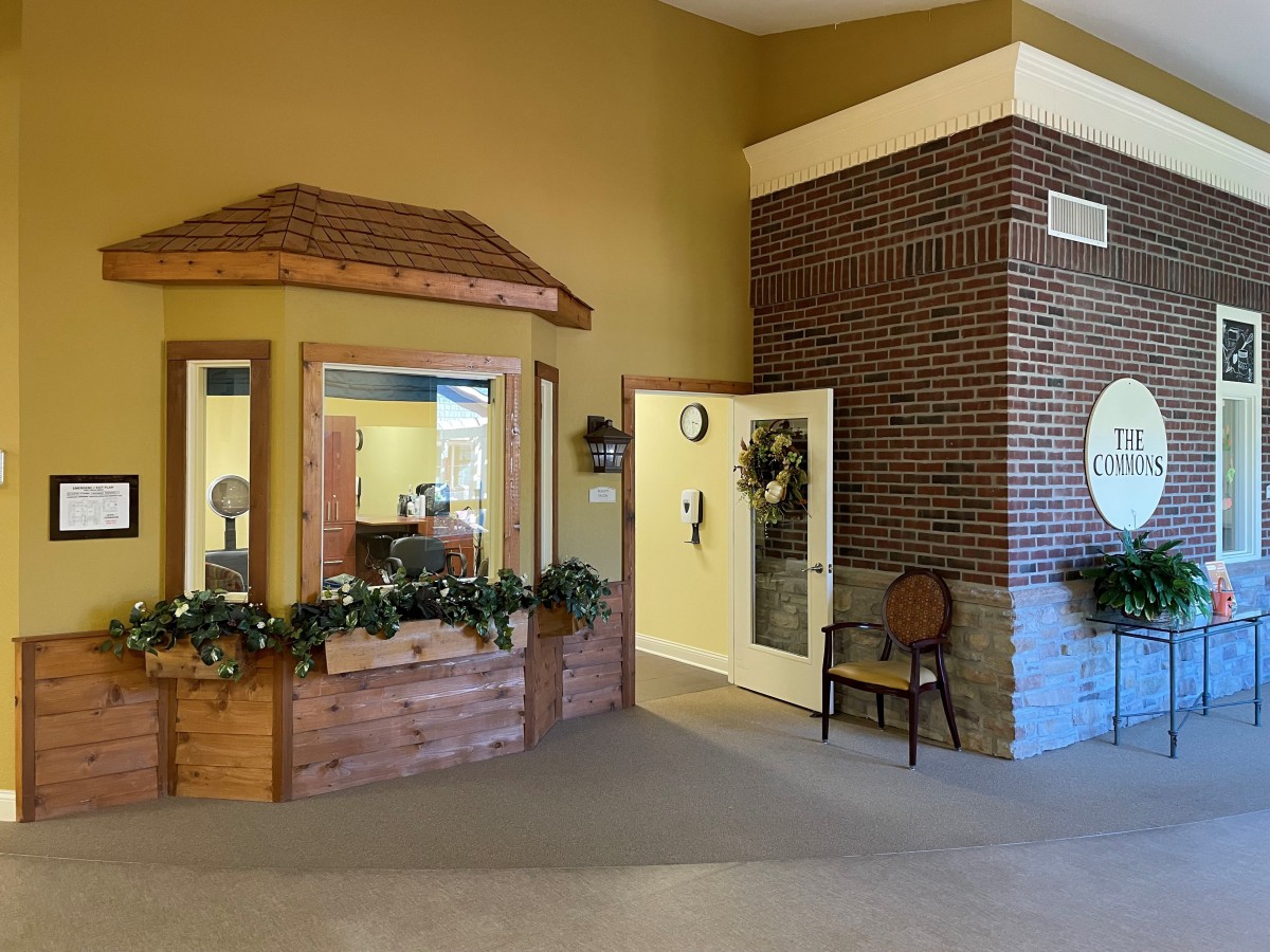 A cozy reception area with decorative plants and a brick wall.