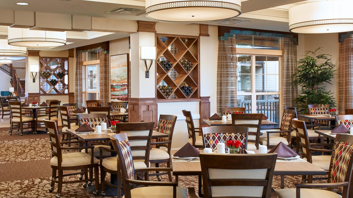 A cozy and elegant restaurant dining area with neatly arranged tables and chairs, featuring a stylish wine rack and tasteful decor.