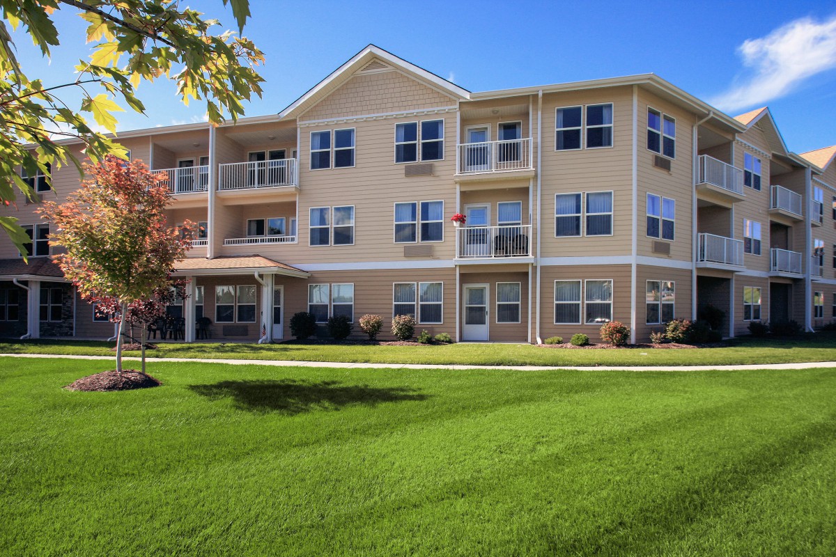 A multi-story residential apartment building with a well-maintained lawn.