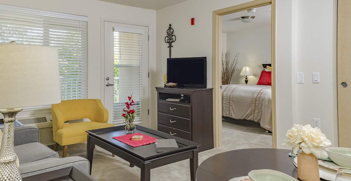 A cozy apartment interior featuring a living room with modern furniture and a view into the bedroom.