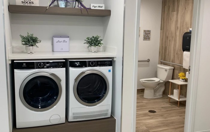 A modern laundry area with a washer and dryer next to a bathroom.
