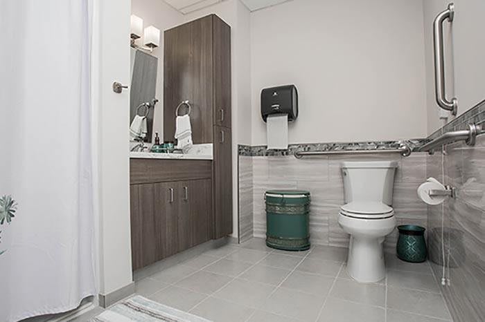 A clean and modern bathroom with a toilet, sink, and paper towel dispenser.