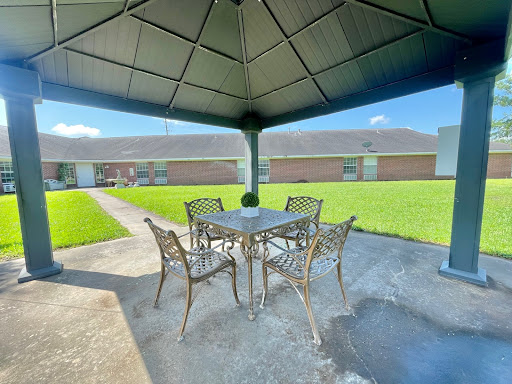 A cozy outdoor gazebo with a dining set, surrounded by lush green grass.