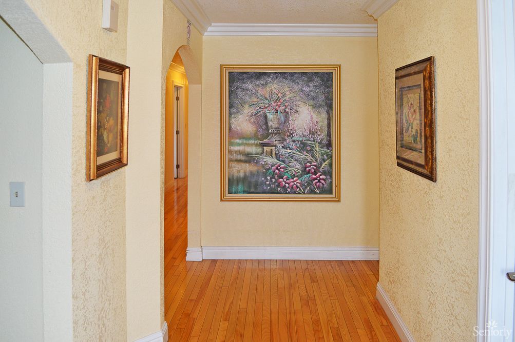 A hallway with framed paintings on the walls and a polished wooden floor.