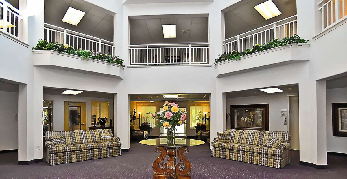A spacious lobby with a seating area, floral centerpiece on a table, and decorative lighting.
