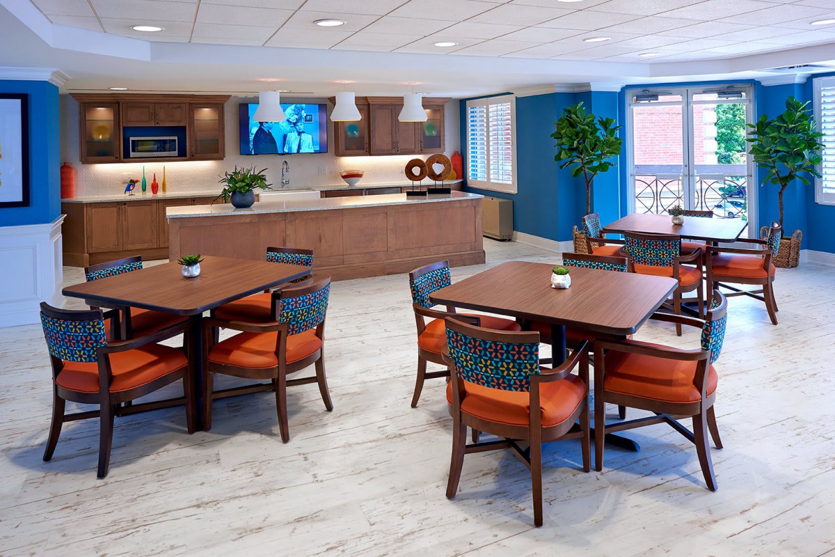 A modern dining area with wooden tables and chairs, featuring contemporary decor and lighting.
