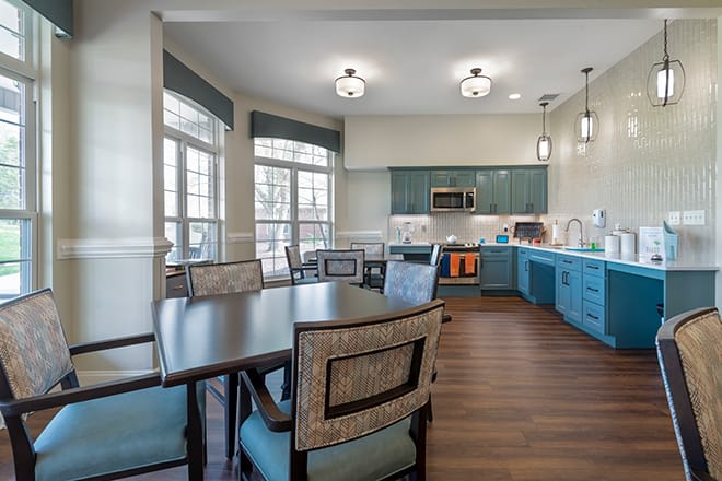 A modern kitchen and dining area with hardwood floors, large windows, and stylish lighting.