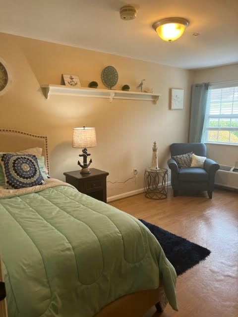 A cozy bedroom with a green bedspread, lamp, and natural light.