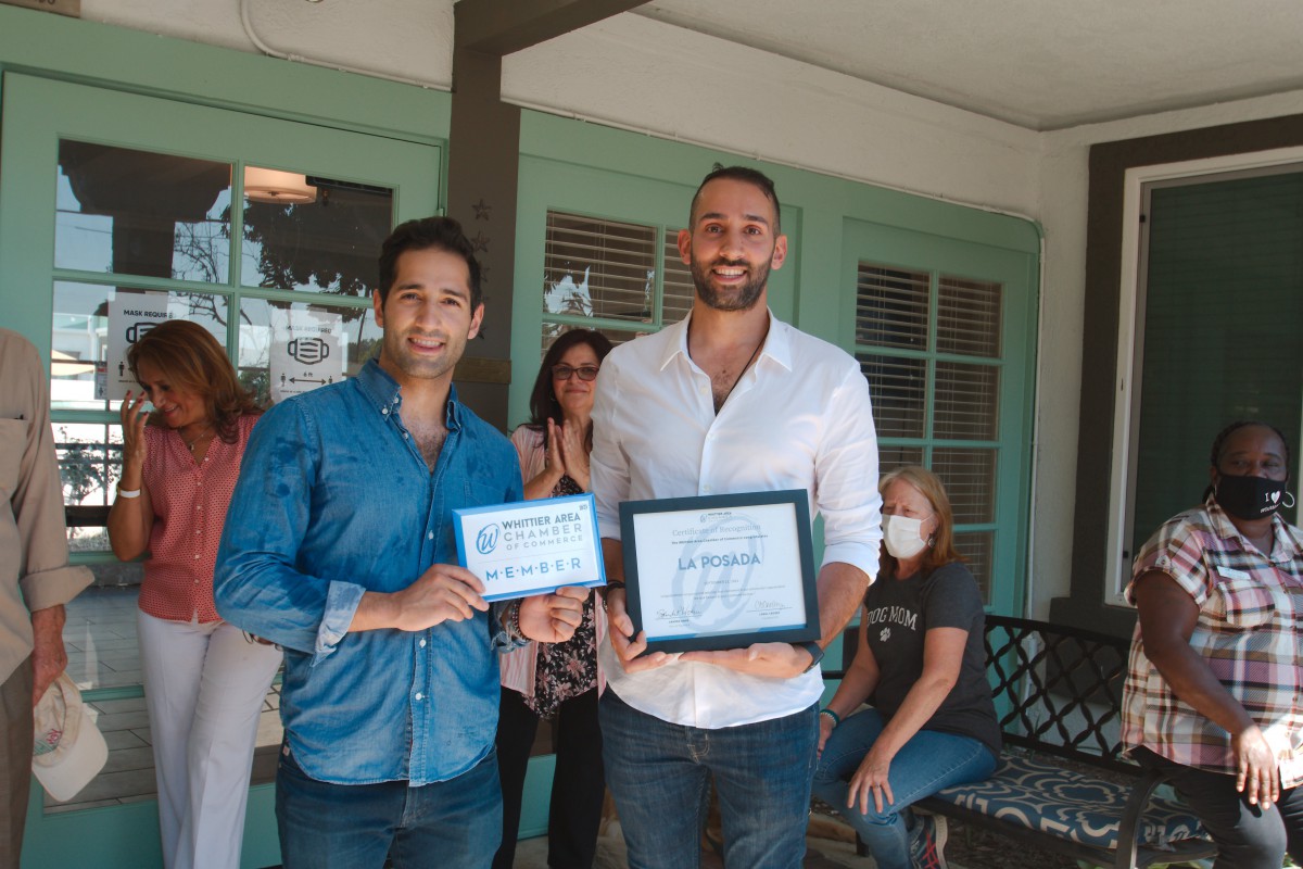 Two men holding certificates at an event, surrounded by other people.