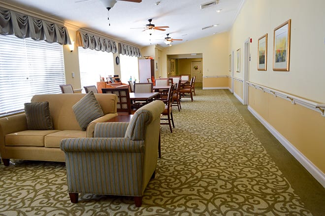 A cozy living area with comfortable seating, tables, and large windows allowing natural light.