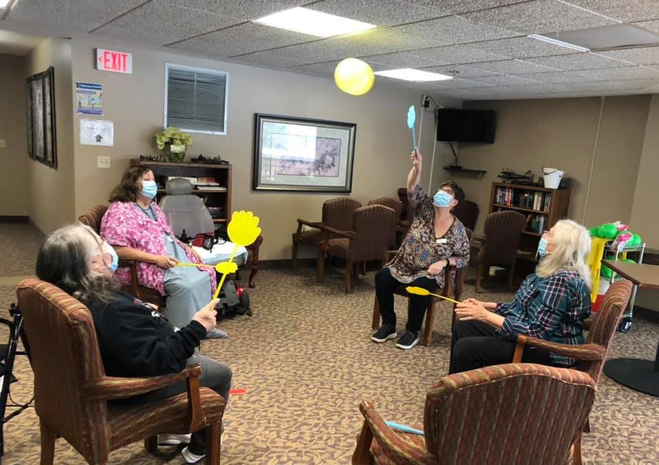 A group of elderly individuals enjoying a balloon game indoors.