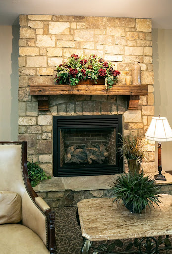 Cozy living room featuring a stone fireplace adorned with floral arrangements.