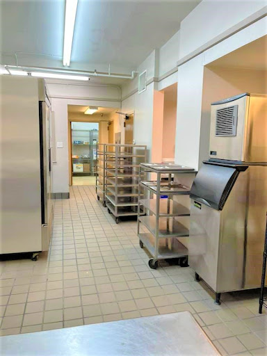A well-organized commercial kitchen featuring stainless steel refrigeration units and food storage carts.