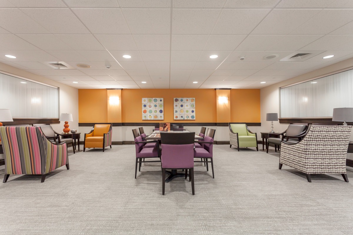 A spacious and well-lit meeting room with colorful chairs and tables, designed for gatherings or conferences.