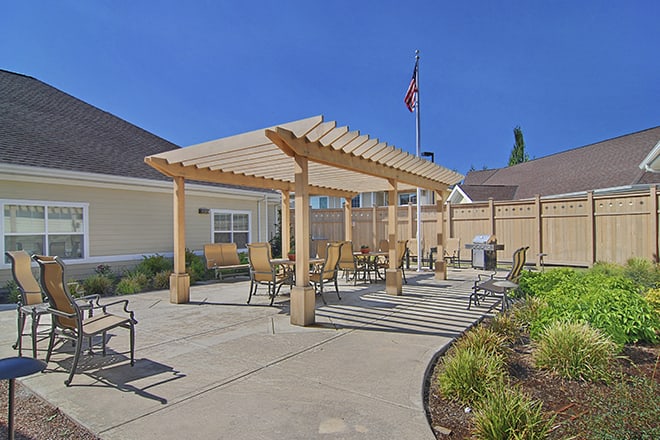 A sunny patio with a wooden pergola and outdoor seating.