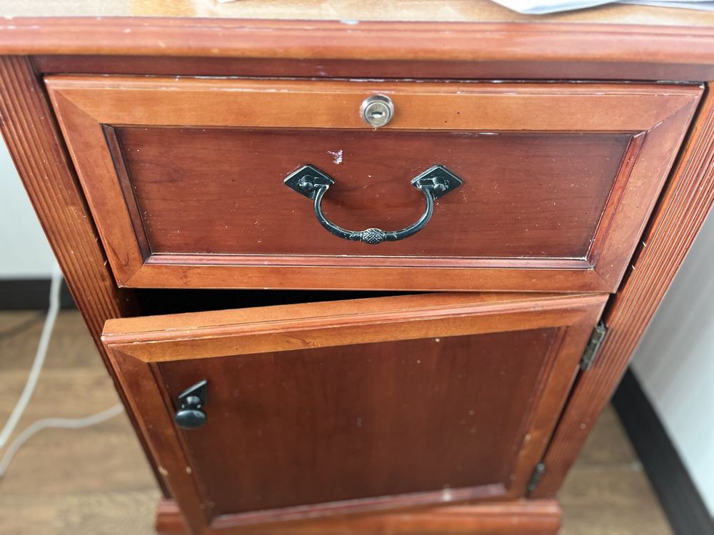 A vintage wooden cabinet with a drawer and door, featuring metal handles.