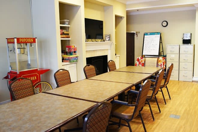 A meeting room with a long table, several chairs, a TV, and a popcorn machine.