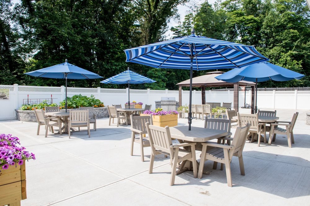 An outdoor patio area with tables, chairs, and blue umbrellas on a sunny day.