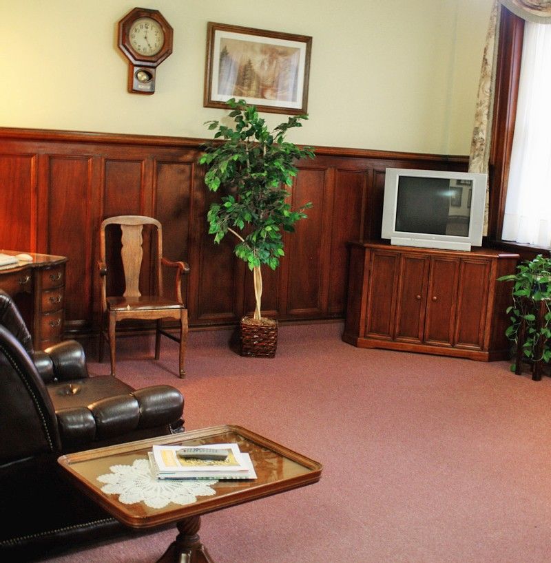 A vintage-style living room featuring wood paneling, a small television, and traditional furnishings.