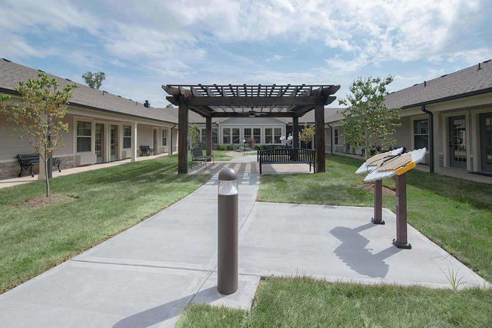 A well-maintained courtyard featuring a pergola, surrounded by buildings and greenery.