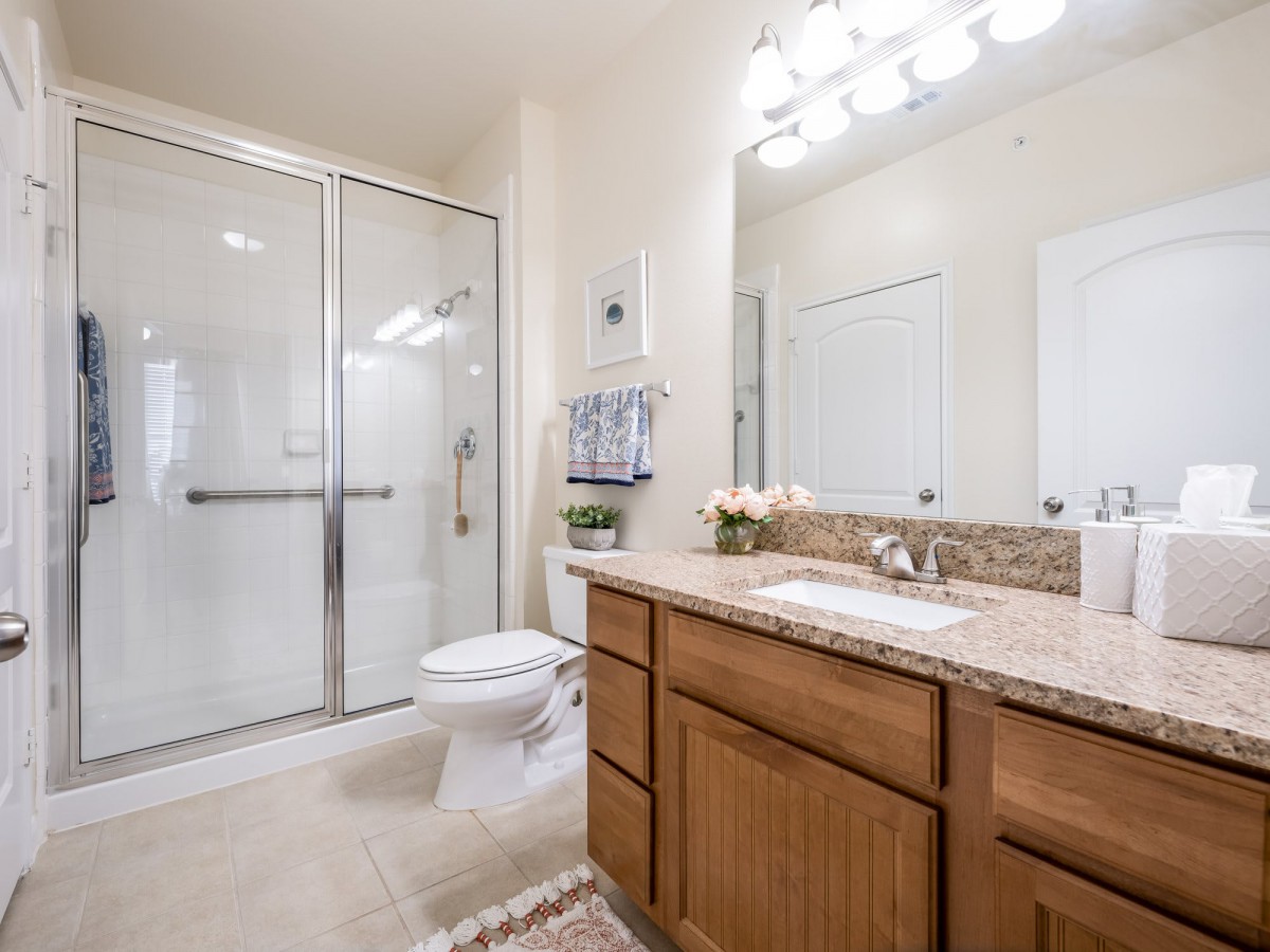 A modern bathroom featuring a shower, vanity with sink, and toilet.