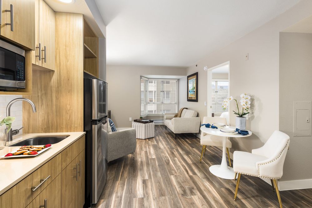 A modern living room and kitchen with wood flooring and stylish furniture.