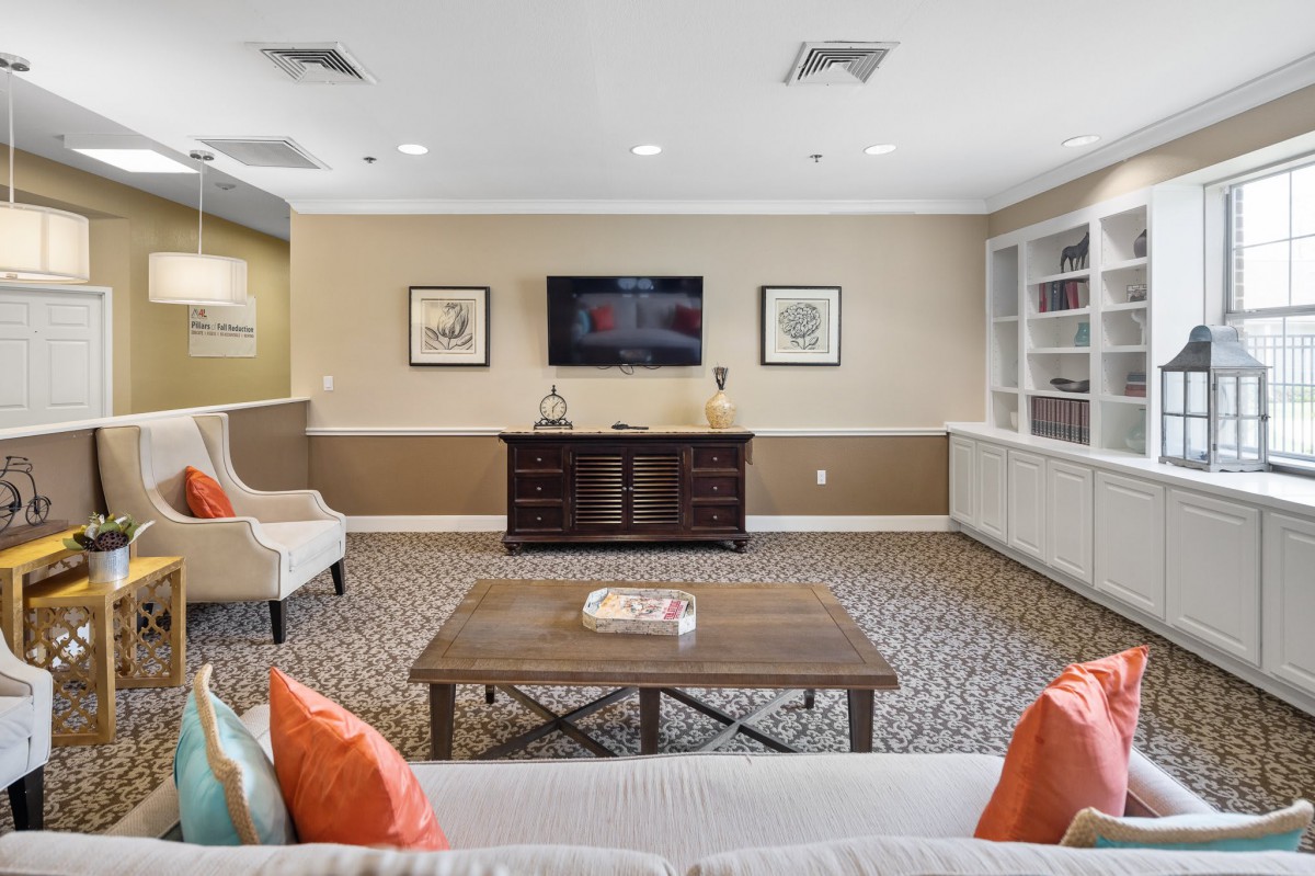 A cozy living room with a TV mounted on the wall, surrounded by comfortable seating and tasteful decor.