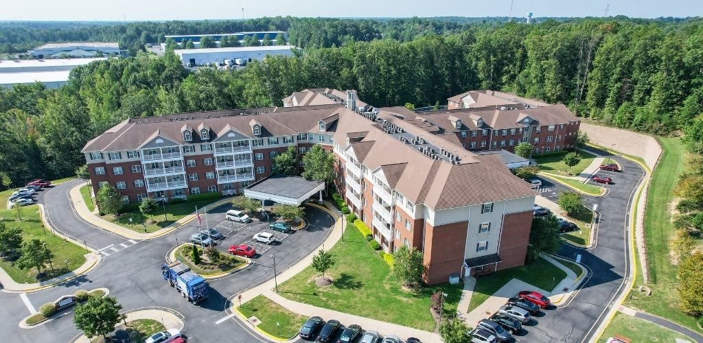 Aerial view of a residential building with a surrounding parking area and greenery.