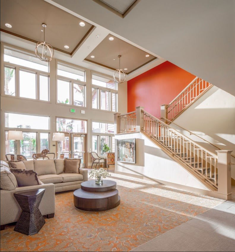 Spacious living room with a modern design, featuring large windows and an orange accent wall.