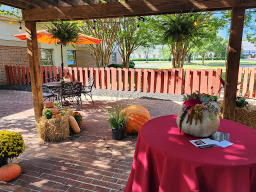 A cozy outdoor patio area decorated for a fall event, featuring pumpkins and vibrant plants.