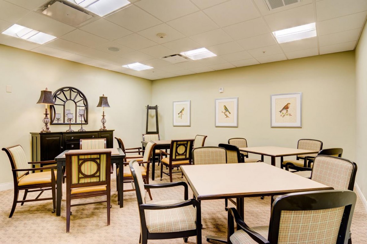 An elegantly furnished dining area with tables and chairs, decorated with wall art and ambient lighting.