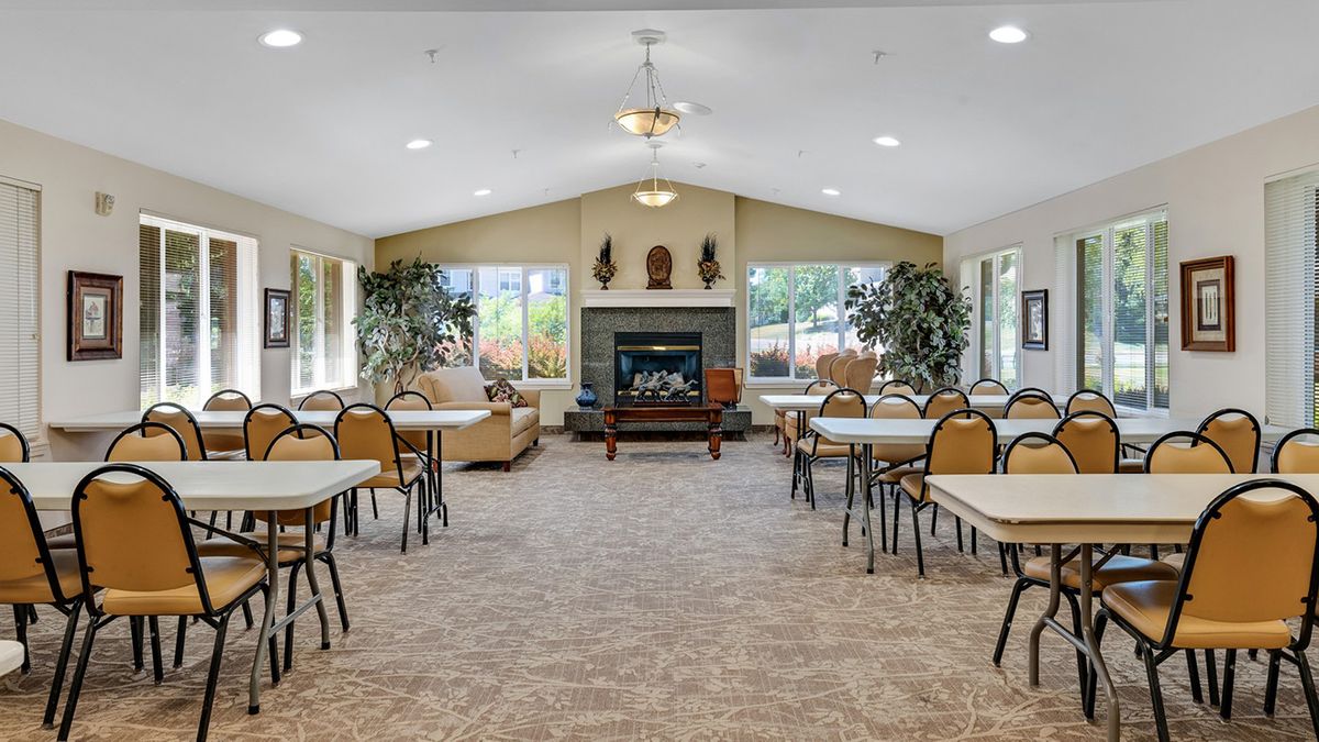 A spacious dining area with tables and chairs, featuring a fireplace and large windows.
